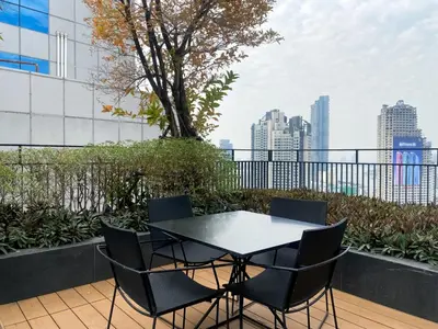 a table and chairs on a balcony with a city skyline at Contemporary Stylish 1BR - Ultra Fast Wifi - Silom in Bangkok