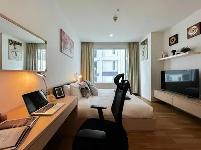a hotel room with a bed and a desk with a laptop at Modern Expansive - Ultra Fast WiFi - BTS Phrom Phong in Bangkok