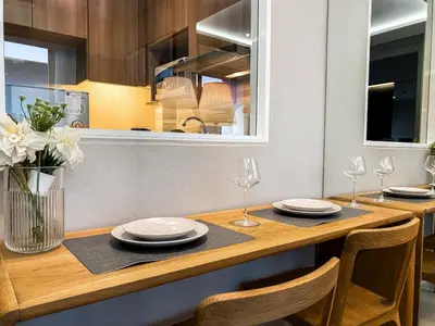 a kitchen with a wooden table with plates and wine glasses at Exquisite Modern 1BR - Ultra Fast Wifi - BTS Thong Lo in Bangkok