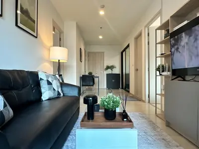 a living room with a black couch and a tv at Luxury City-Scape 2BR - Ultra Fast Wifi - Asoke in Bangkok