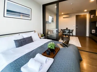 a bedroom with a bed with a laptop on a table at Cityscape Modern Apt - Ultra Fast Wifi - Phra Khanong in Bangkok