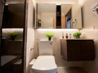 a bathroom with a toilet and a sink and a mirror at Cityscape Modern Apt - Ultra Fast Wifi - Phra Khanong in Bangkok