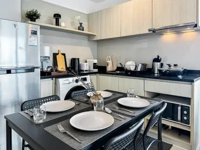 a kitchen with a black table with plates and chairs at Contemporary High-Rise 2BR - Ultra Fast Wifi - Sathorn in Bangkok