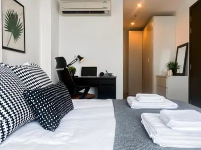 a bedroom with a bed with pillows and a desk at Contemporary High-Rise 2BR - Ultra Fast Wifi - Sathorn in Bangkok