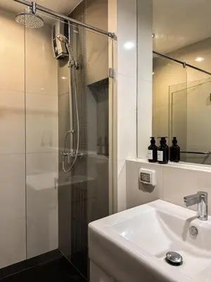 a white bathroom with a shower and a sink at Contemporary High-Rise 2BR - Ultra Fast Wifi - Sathorn in Bangkok