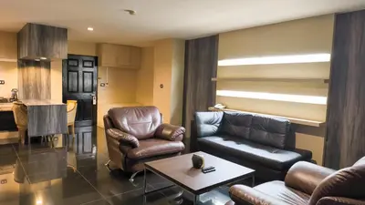 a living room with leather furniture and a kitchen at Avana Bangkok Hotel & Convention Centre in Bangna