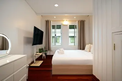a white bedroom with a bed and a television at 2BR 1BA Home In Yaowarat 5 Min MRT Nivas Wanit ECO in Bangkok