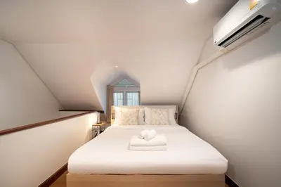 a small bedroom with a white bed in a attic at 2BR 1BA Home In Yaowarat 5 Min MRT Nivas Wanit ECO in Bangkok