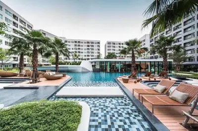 a pool with chairs and palm trees and a building at Gfeel X Elio Sukhumvit64 in Bangkok