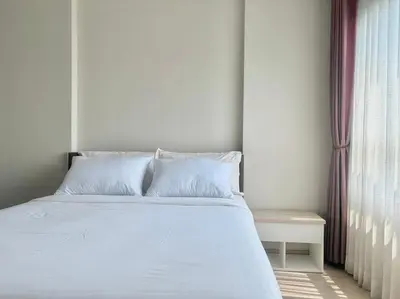 a bed with white sheets and pillows next to a window at Gfeel X Elio Sukhumvit64 in Bangkok