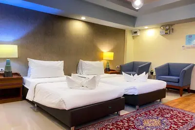 a hotel room with two beds and a chair at Kim Hotel At Morleng in Bangkok