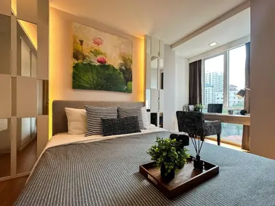 a bedroom with a large bed and a table with a plant at Contemporary Premier 1BR - Ultra Fast Wifi - BTS Nana in Bangkok
