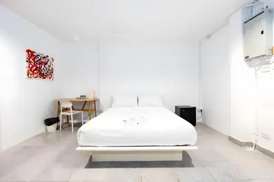 a white bedroom with a bed and a table at XX Mitr INN Sukhumvit 2 - BTS Nana in Bangkok