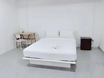 a white bed in a white room with a table at XX Mitr INN Sukhumvit 2 - BTS Nana in Bangkok