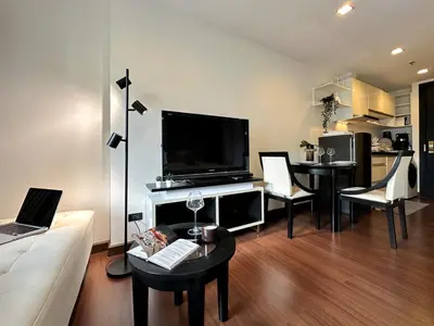 a living room with a television and a table with chairs at Modern Cityscape1BR - Ultra Fast WiFi - BTS On nut in Bangkok