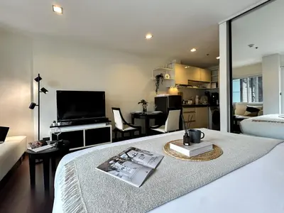 a bedroom with a bed with a television and a living room at Modern Cityscape1BR - Ultra Fast WiFi - BTS On nut in Bangkok