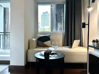 a living room with a couch and a table with a laptop at Modern Cityscape1BR - Ultra Fast WiFi - BTS On nut in Bangkok