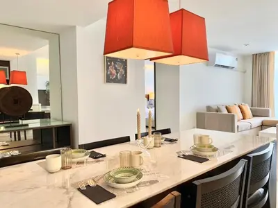 a kitchen and living room with a large table with red cabinets at Sathorn Prime Residence 2BR #Bangkok in Bangkok