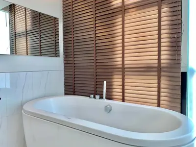 a white bath tub in a bathroom with wooden windows at Sathorn Prime Residence 2BR #Bangkok in Bangkok