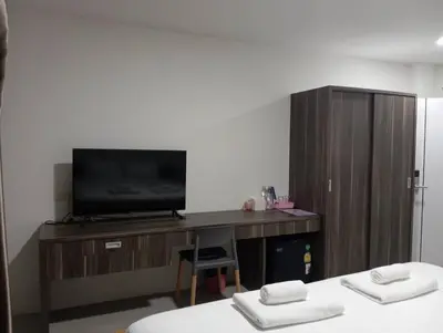 a room with two beds and a tv and a desk at VS Place in Nonthaburi