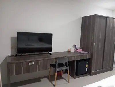 a television on a wooden entertainment center with a chair at VS Place in Nonthaburi