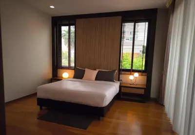 a bedroom with a large bed and two windows at Studio Sukumvit 29 in Bangkok
