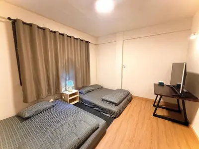 a bedroom with two beds and a television in it at Holy Hostel Sathorn in Thung Maha Mek