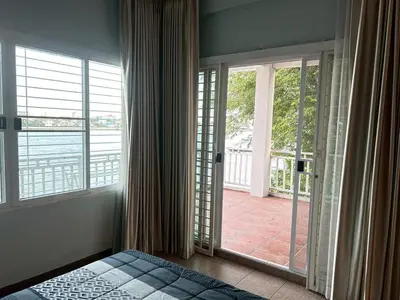 a bedroom with a bed and a door to a balcony at บ้านริมน้ำ bann rim num in Bangkok