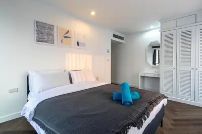 a bedroom with a large bed with a blue pillow on it at Omni Nuvél 4 Sukhumvit Branded Suites in Bangkok