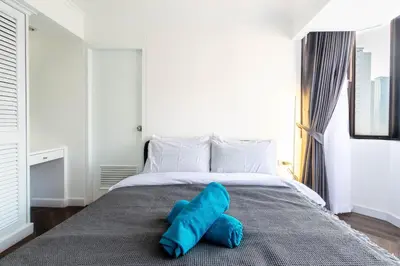 a bed with two blue pillows on top of it at Omni Nuvél 4 Sukhumvit Branded Suites in Bangkok