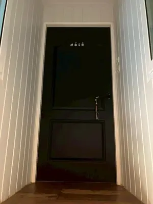 a black door with a small toy figure on it at Cat in the box homestay in Godown