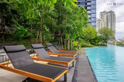 a row of chaise lounge chairs next to a swimming pool at One9Five Asoke Rama 9 \u6708\u79df 500mbps wifi in Bangkok