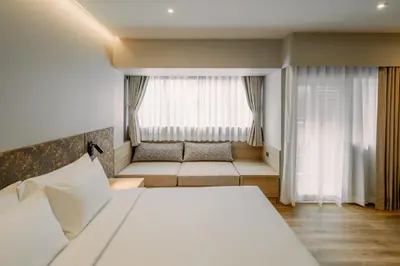 a bedroom with a bed and a couch in front of a window at Away Bangkok Sukhumvit in Bangkok