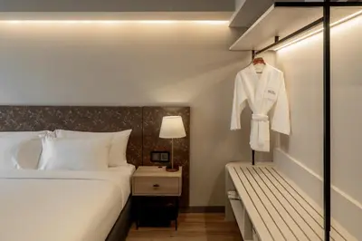 a bedroom with a bed and a white suit on a rack at Away Bangkok Sukhumvit in Bangkok