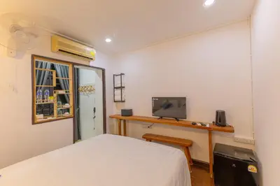 a bedroom with a bed and a desk with a tv at Calmly Stay Ratchada in Bangkok