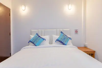 a large bed with white sheets and blue pillows at Calmly Stay Ratchada in Bangkok
