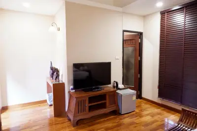 a living room with a flat screen tv on a wooden entertainment center at Yotaka Boutique Hotel Bangkok in Bangkok