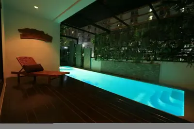 a swimming pool with a chair next to a table at Yotaka Boutique Hotel Bangkok in Bangkok