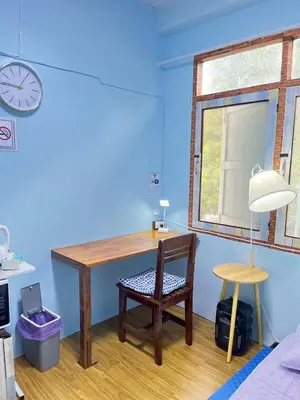 a desk in a room with a chair and a clock at 214 Lovely apartment with private bathroom and WiFi in Bangkok