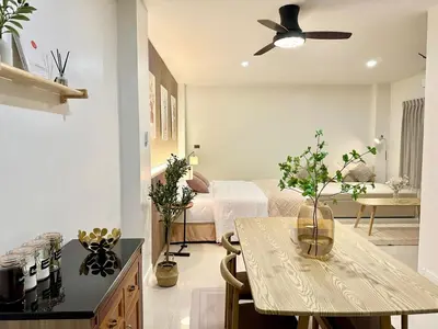 a room with a bed and a table with flowers on it at Studio Botanica I 2 mins to SRT in Bangkok