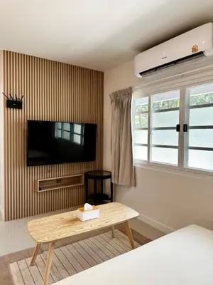 a living room with a tv and a wooden coffee table at Indigo Studio 2 mins from SRT Wat Samien Nari in Bangkok