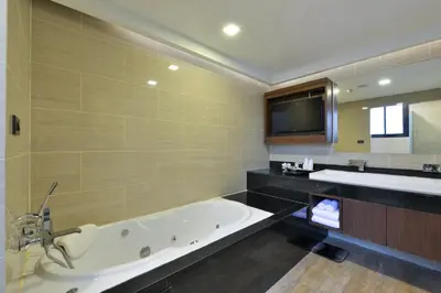 a large bathroom with a tub and a tv at Syama Suite Sukhumvit 20 in Bangkok