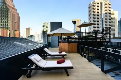 a balcony with two chairs and umbrellas on a building at Syama Suite Sukhumvit 20 in Bangkok