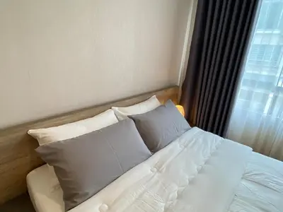 a bed with white sheets and pillows in a room at Cozy home near impact arena in Nonthaburi