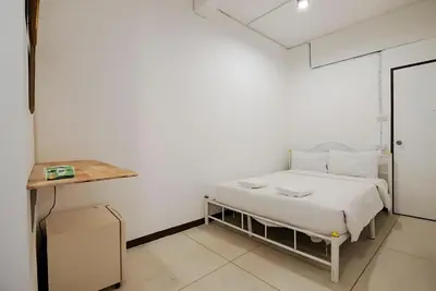 a white bedroom with a bed and a table at XX GO INN Asiatique Bangkok - โกอินน์ เอเชียทีค เจริญกรุง in Bangkok