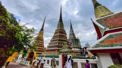 a group of pagodas in a building with people sitting at XX GO INN Asiatique Bangkok - โกอินน์ เอเชียทีค เจริญกรุง in Bangkok