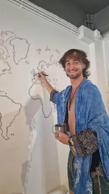 a man painting a wall in a room at Casita Hostel House Bangkok in Bangkok