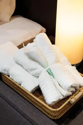 a pile of white towels on a basket with a lamp at Azure Dreams King Suite Retreat near BTS & Fast WiFi in Khlong Toei