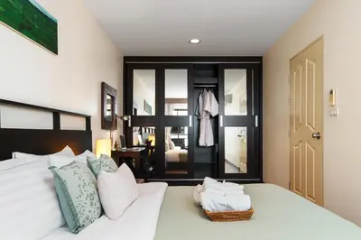 a bedroom with a white bed with towels on it at Verdant Vista King Suite near BTS with Modern Amenities in Khlong Toei