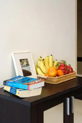 a table with a bowl of fruit and books at Verdant Vista King Suite near BTS with Modern Amenities in Khlong Toei